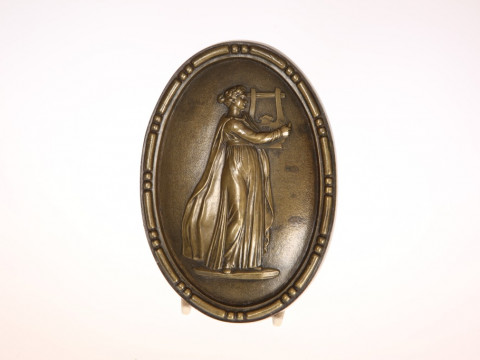 A 19TH CENTURY BRONZE PLAQUE, oval, cast with Apollo playing the lyre....