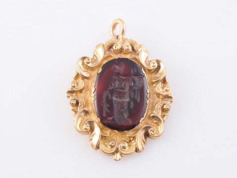 A CARNELIAN AND GILT METAL PENDANT, the carved oval carnelian depicting...
