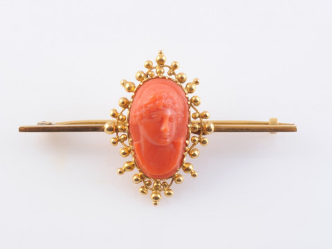 A CORAL AND YELLOW METAL CAMEO BROOCH, the oval cameo carved to depict...