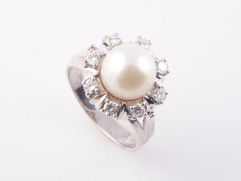A CULTURED PEARL AND DIAMOND RING, the single cultured pearl set raised...