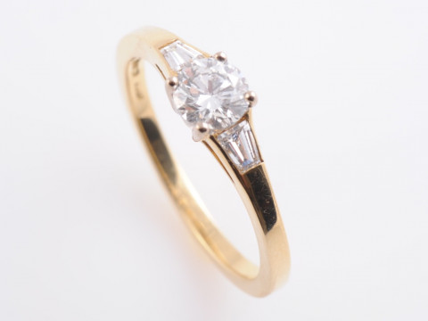 A DIAMOND RING, the brilliant cut diamond four claw set between tapering...