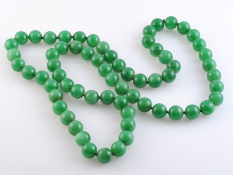 A JADEITE BEAD NECKLACE, the sixty-six uniform polished jadeite beads...