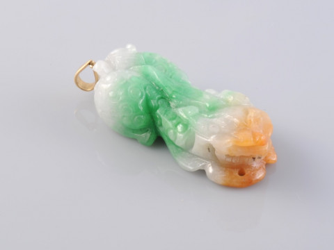 A JADEITE PENDANT, carved to depict a sleeping Chinese dragon, with an...