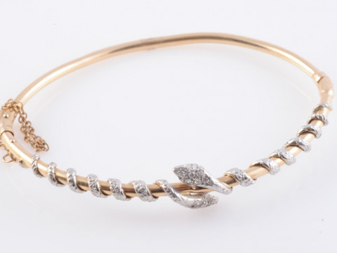 A LATE VICTORIAN DIAMOND SET BANGLE, set to the top section with two snakes,...