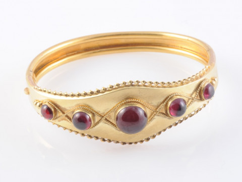 A MID VICTORIAN GARNET SET BANGLE, the five graduating round cabochon...