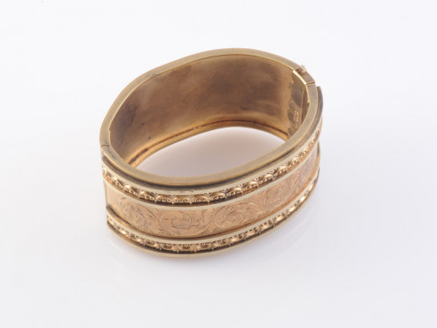A MID VICTORIAN GILT METAL BANGLE, set to the top with a symmetrical design...