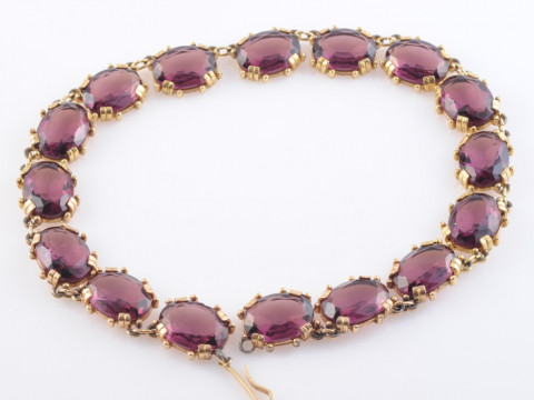 A PASTE AND GILT METAL NECKLACE, the sixteen large oval purple coloured...