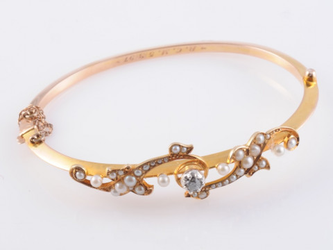 A SEED PEARL AND DIAMOND BANGLE, the single old cut diamond claw set to...