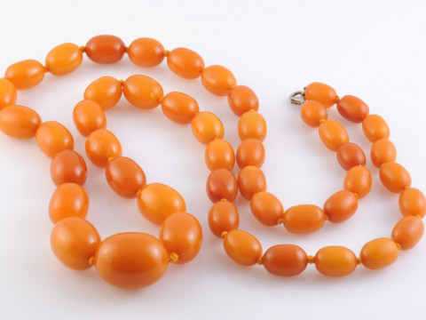 AN AMBER NECKLACE, the forty-seven graduating oval beads strung knotted...