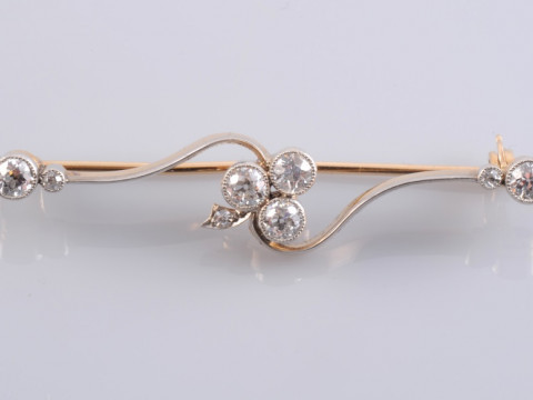 AN EDWARDIAN DIAMOND BROOCH, the cross over twist style mount set to the...