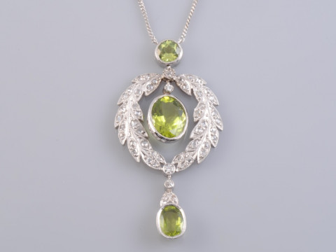 AN EDWARDIAN PERIDOT AND DIAMOND PENDANT, the oval cut pendant collet...