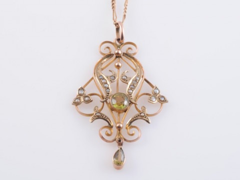 AN EDWARDIAN PERIDOT, SEED PEARL AND 15 CARAT GOLD PENDANT, in Art Nouveau...