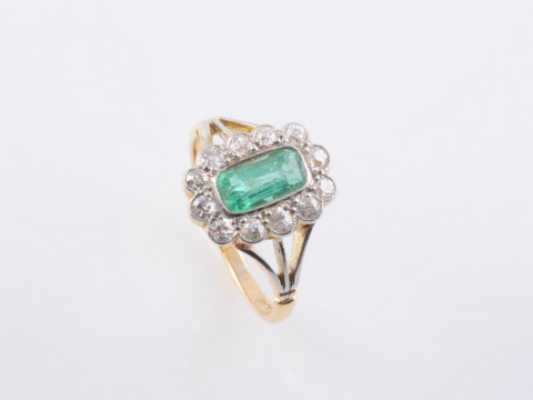 AN EMERALD AND DIAMOND RING, the rectangular cut emerald collet set within...