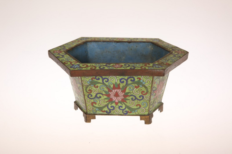 A SMALL CHINESE CLOISONNE ENAMEL JARDINIERE, of hexagonal form, decorated with foliate patterns against a green ground, on shaped feet. Width 19.5cm