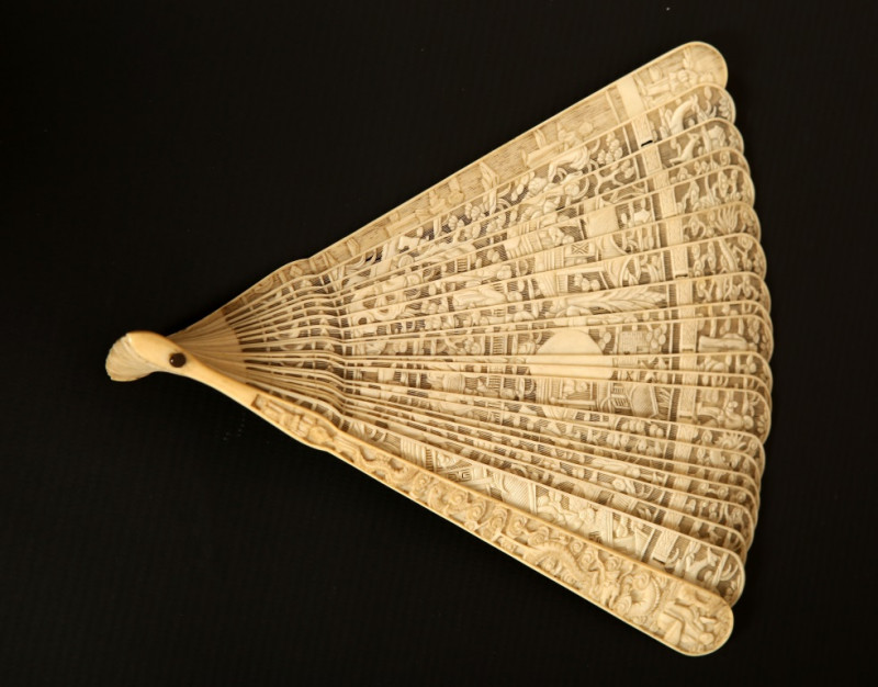 A CANTON IVORY BRISE FAN, 19th CENTURY, elaborately carved with figures in pavilions and landscapes, the terminals in relief with dragons and figures and the central oval cartouche unengraved. 19cm