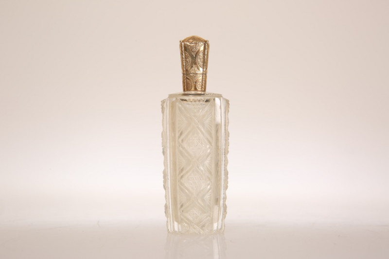 A GOLD TOPPED SCENT FLASK, 19TH CENTURY, the Dutch gold mount (acorn leaf mark) engraved with conjoined oval cartouches and pendant foliage, the tapering body with cut decoration. 9cm