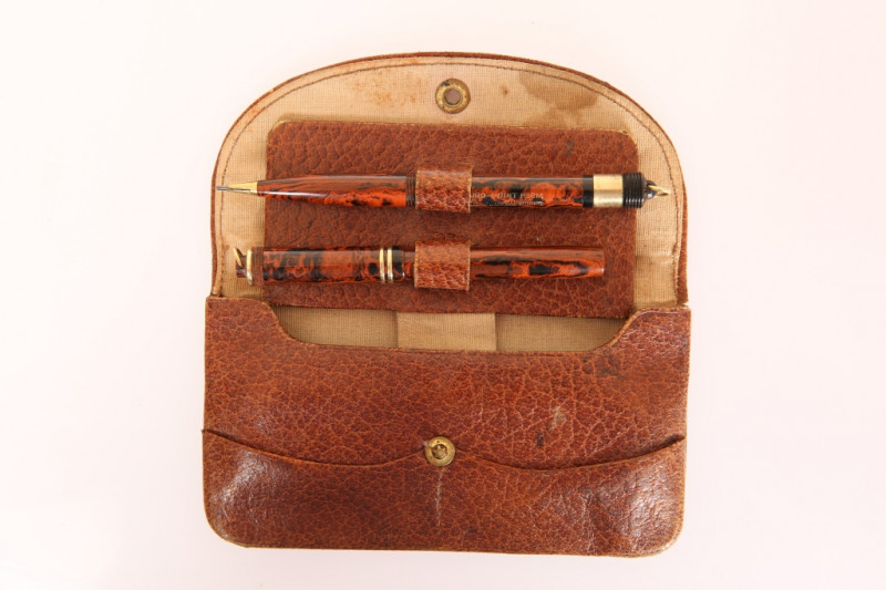 A CONWAY STEWART PEN AND PENCIL SET, in red marbled finish, the Dinkie no. 526M fountain pen with 14ct gold nib, the propelling pencil a Duro-Point no. 2M, in a leather case. 