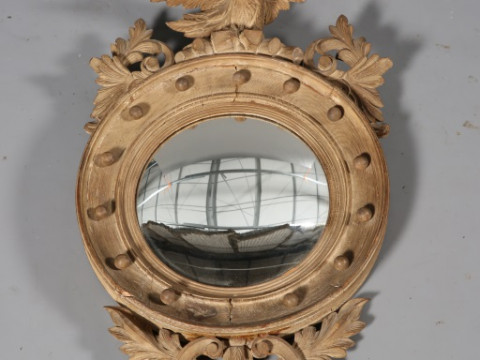 A REGENCY CARVED CONVEX MIRROR, with eagle crest and scrolling foliage....