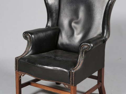 A GEORGE III STYLE LEATHER UPHOLSTERED MAHOGANY WING CHAIR, with serpentine...