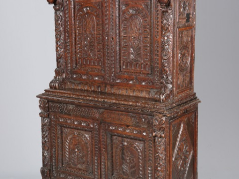 A CARVED OAK CUPBOARD, with shaped cornice above a drawer over a pair...