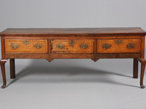 A GEORGE III OAK DRESSER BASE, with moulded rectangular top above three...