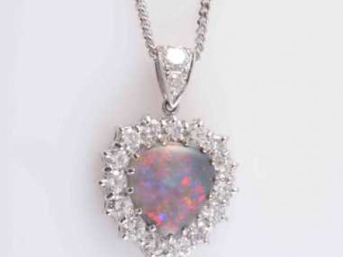 AN OPAL AND DIAMOND PENDANT, the heart shaped opal claw set within a surround...