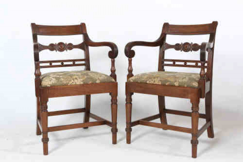 A pair of Regency mahogany carvers, each with reeded arms and splat, raised on tapering turned legs joined by an H-stretcher.