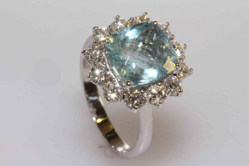 18 carat gold, cushion shaped aquamarine and round brilliant cut diamond cluster ring, aquamarine approximately 3.38 carats, total diamond weight approximately 1.15 carats, size M