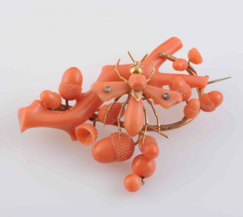 A MID 19TH CENTURY CORAL BROOCH, ornately carved to depict a branch with multiple acorn highlights, set to the centre with a winged insect with two old cut diamond highlights to the wings and gold work highlights for the legs and head, set on brooch pin f