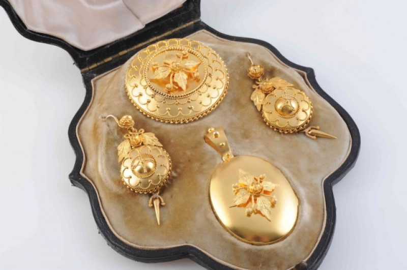 A MID VICTORIAN DEMI-PARURE, comprising locket pendant, locket brooch and a pair of earrings, each with intricate floral and foliage detailing of textured and polished metal with subtle beaded and scrolling metal details around the perimeter of the earrin