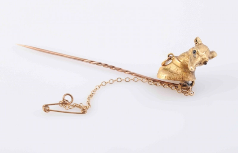 A MID VICTORIAN STICK PIN, modelled as the head of a greyhound with moulded articulated collar set with a single turquoise highlight, with attached safety chain. In fitted case. Length 7cm. Weight 4.9 grams