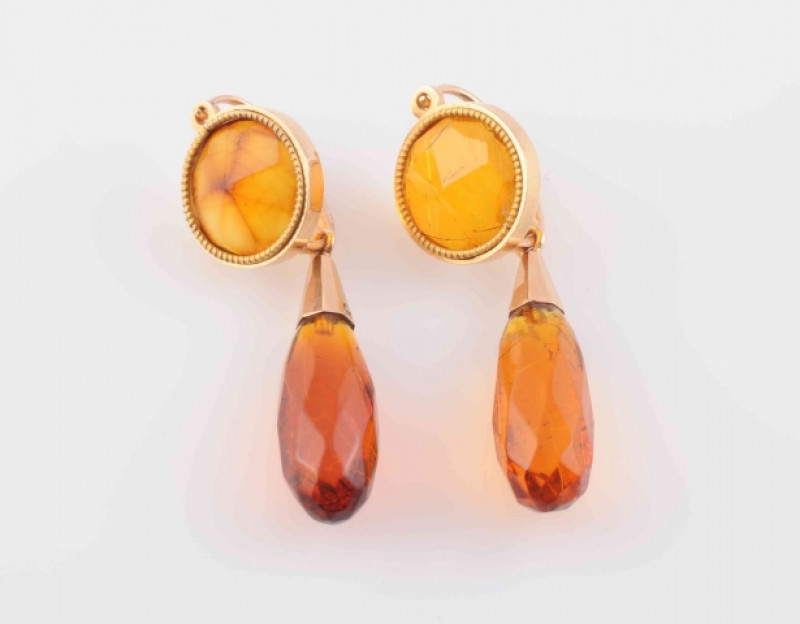 A PAIR OF PASTE SET EARRINGS, the tapering oval amber coloured faceted bead suspending from an articulated link from a round cut faceted amber bead, on hook style fittings. Total weight 6.3 grams.