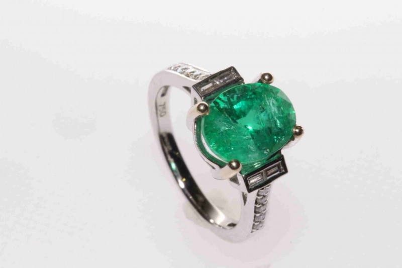 18 carat gold, oval emerald ring with baguette and round brilliant diamond shoulders, emerald approximately 3.5 carats, size M