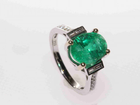 18 carat gold, oval emerald ring with baguette and round brilliant diamond...