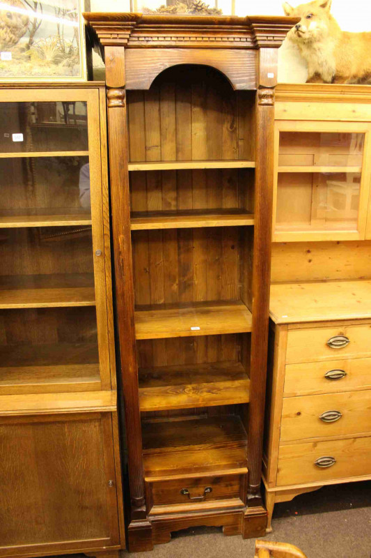 Slim stained pine open bookcase having four adjustable shelves above a single drawer