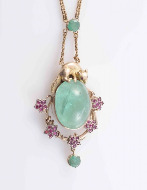 AN EMERALD AND RUBY PENDANT, the large oval cabochon cut emerald collet set within a moulded metal work mount depicting a branch set with five flowerhead shape mounts each set with five ruby highlights, suspending an articulated round cut emerald drop, al