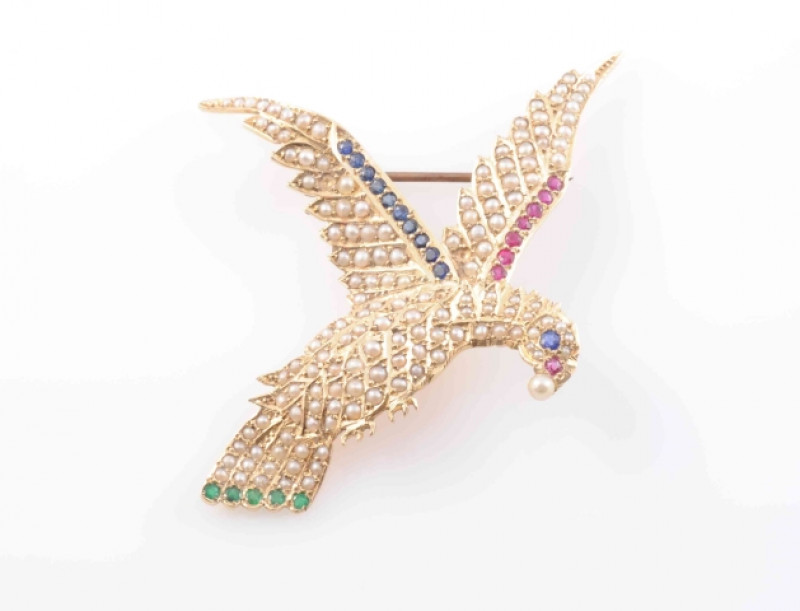 A SEED PEARL, EMERALD, RUBY AND SAPPHIRE BROOCH, modelled as a bird in flight, set throughout with seed pearl highlights and subtle round cut ruby, emerald and sapphire highlights to the wings and tail, with further ruby and sapphire highlights to the eye