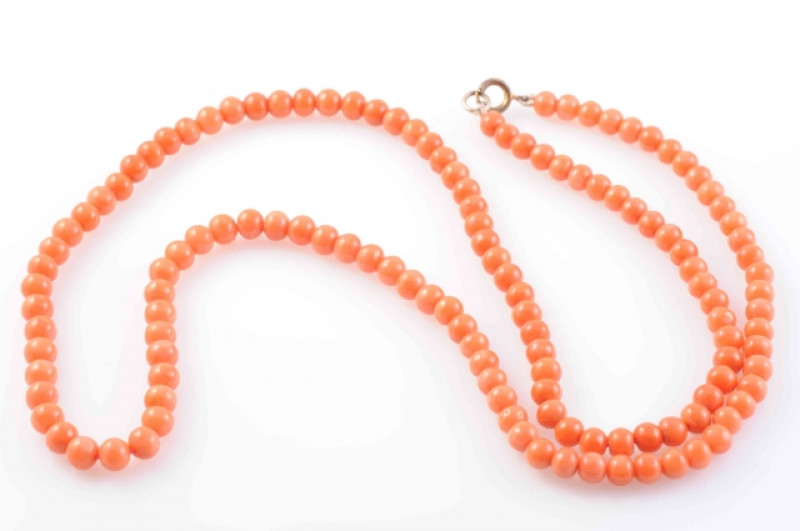 A CORAL NECKLACE, the one hundred and thirty-two polished coral beads strung simply on to bolt ring clasp. Total length 67cm. Weight 34 grams.