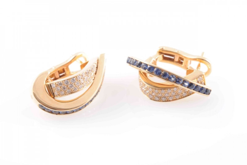 A PAIR OF SAPPHIRE AND DIAMOND EARRINGS, the curved crossover style mounts set to one strand with fifteen round cut sapphire highlights, and thirty brilliant cut diamond highlights to the other, on post and clip fittings. Total weight 10.3 grams.