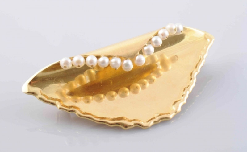 A CONTEMPORARY GOLD AND SEED PEARL BROOCH BY CHARLES FRANCIS HALL, LONDON 1988, the abstract shell style brooch with moulded scalloped edge detailing and twelve uniform seed pearl highlights, on brooch pin fitting. Stamped 750. Marked CFH. Width 6cm. Weig