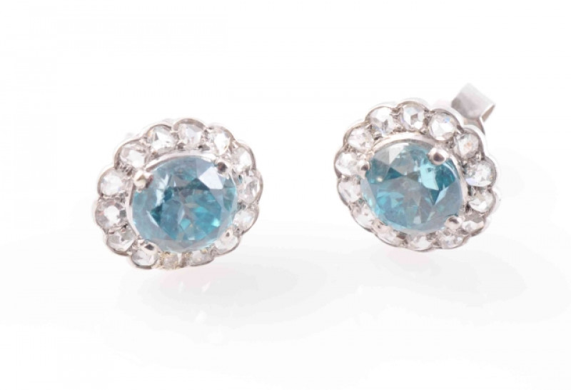 A PAIR OF BLUE ZIRCON AND DIAMOND EARRINGS, the round cut blue zircons each four claw set within a surround of fourteen old cut diamond highlights in a scalloped edge mount, on post and scroll fittings. Total weight 2.6 grams.