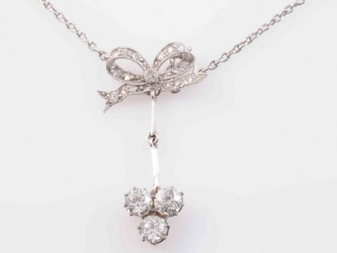 AN EDWARDIAN DIAMOND SET PENDANT, the bow shaped mount set throughout...