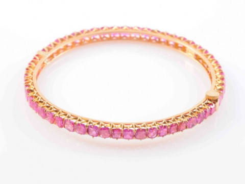 A BURMESE RUBY BANGLE, set to the entirety with fifty-four square mixed...