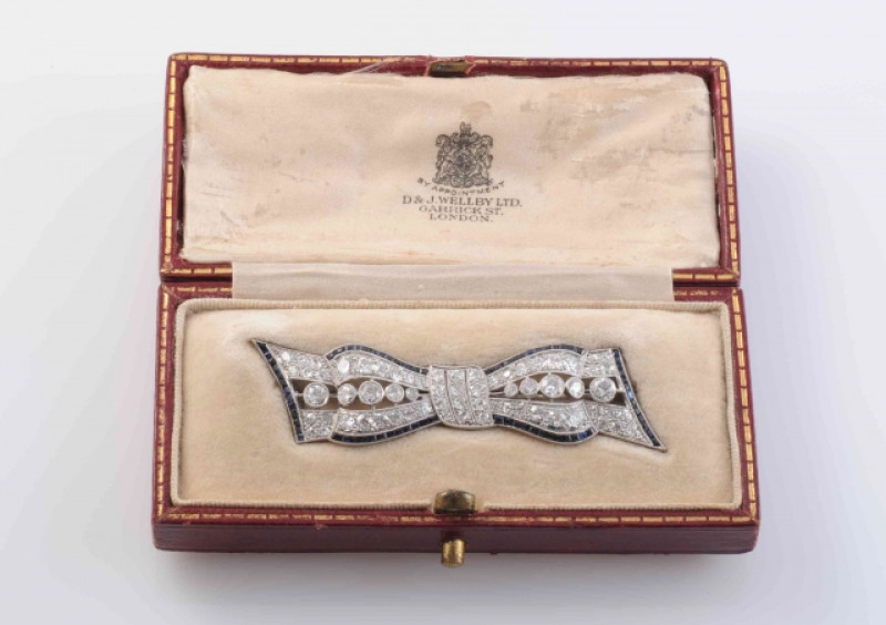 AN EDWARDIAN DIAMOND AND SAPPHIRE BROOCH, modelled as a bow, set to the cut-out centres with ten principal graduating old brilliant cut diamonds and a further fifty-six graduating old brilliant cut diamond highlights and subtle edges set with graduating s