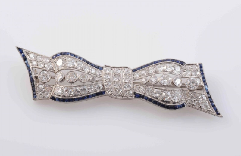 AN EDWARDIAN DIAMOND AND SAPPHIRE BROOCH, modelled as a bow, set to the cut-out centres with ten principal graduating old brilliant cut diamonds and a further fifty-six graduating old brilliant cut diamond highlights and subtle edges set with graduating s