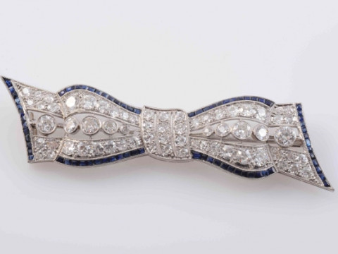 AN EDWARDIAN DIAMOND AND SAPPHIRE BROOCH, modelled as a bow, set to the cut-out centres with ten principal graduating old brilliant cut diamonds and a further fifty-six graduating old brilliant cut diamond highlights and subtle edges set with graduating s thumbnail