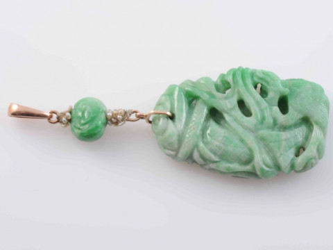 A CHINESE JADEITE PENDANT, the heavily carved large oval jadeite plaque...