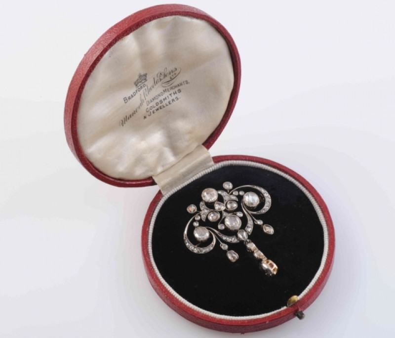 AN EDWARDIAN DIAMOND BROOCH, the symmetrical mount of delicate scroll and floral details suspending three graduating articulated drops, set with five principal round mixed cut collet set diamonds, and a further forty-four graduating old mixed diamond high