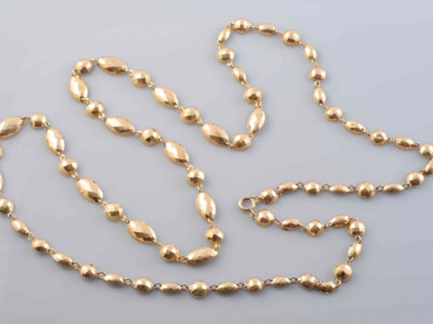 A GOLD COLOURED NECKLACE, formed of alternate circular and oval mounts...