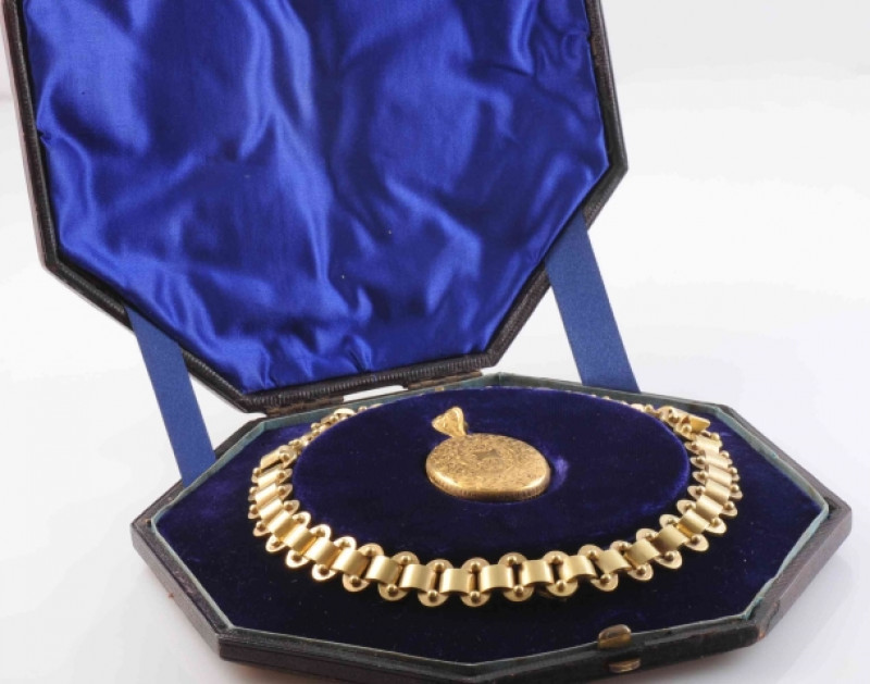 AN EARLY VICTORIAN LOCKET PENDANT, the heavy oval articulated link chain suspending a detachable oval locket pendant set with engraved scrolling and floral details to the entirety, suspending from an articulated tapering oval bale with similar engraved de